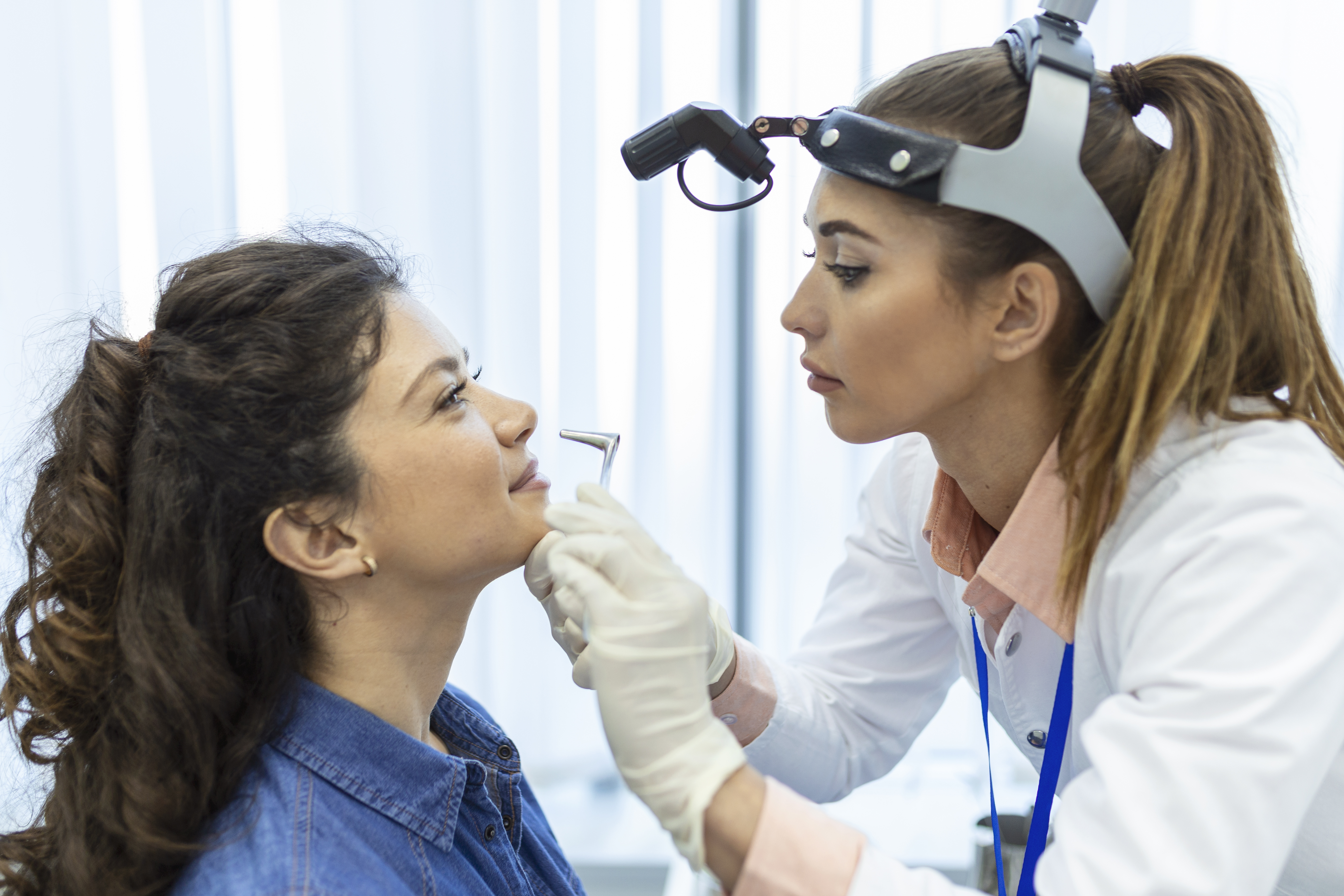Doctor otorhinolaryngologist checking nose with otoscope of patient at hospital. Nasal congestion, sinusitis, allergy concept.